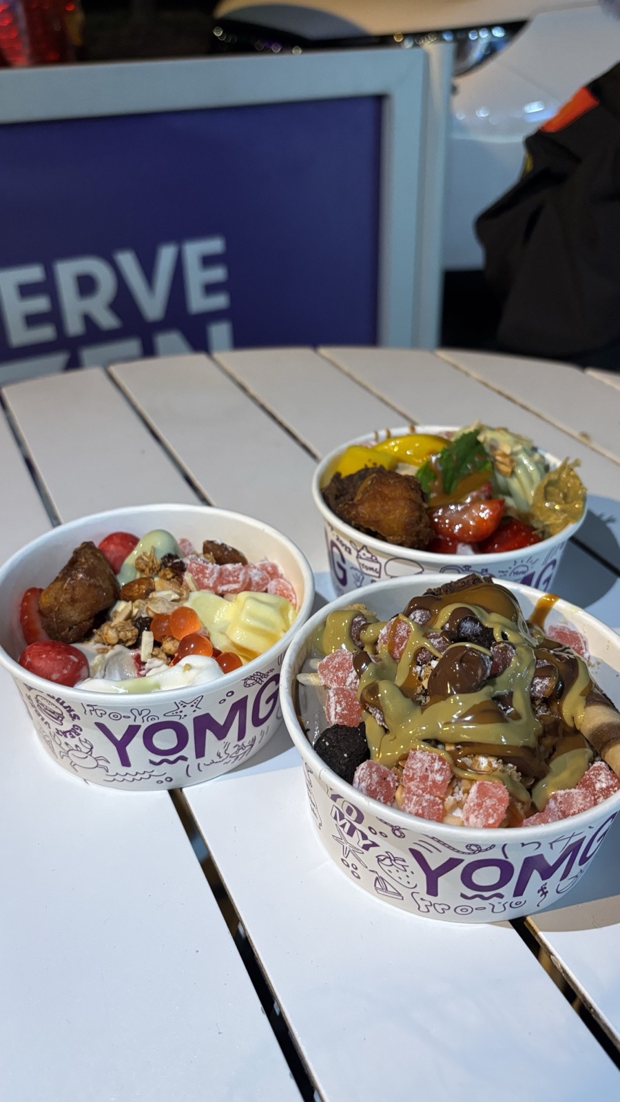 Three colourful YOMG frozen yogurt bowls with toppings